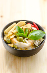Rice noodles in chicken curry sauce with vegetables on wooden background