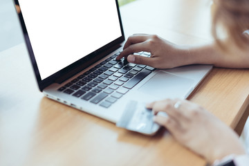 Asian Woman holding credit card and typing keyboard on blank screen laptop with shopping online in selective focus.