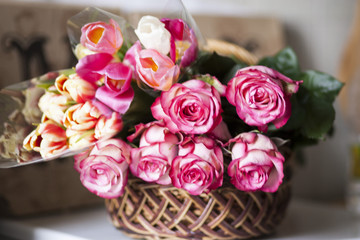 Pink roses and colored tulips are in the basket