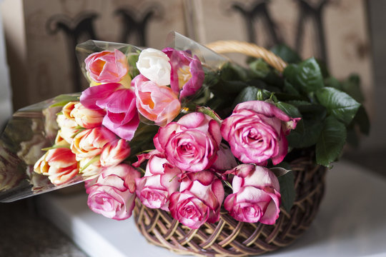 Nice pink roses and colored tulips are in the basket