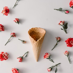 Ice cream cone with colorful flowers pattern on white background. Flat lay. Minimal summer concept.