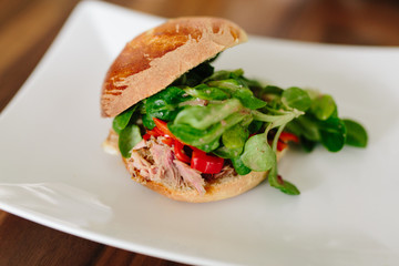 Burger mit Fleisch, Speck und Salat auf weißem Teller