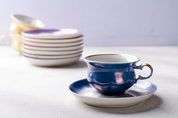 Empty colorful porcelain tableware. Blue cup with plate on lilac background