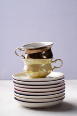 Empty colorful porcelain tableware, cups and plates on lilac background