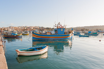 Fototapeta na wymiar Mediterranean traditional colorful boats luzzu. Fisherman village in the south east of Malta. Early winter morning in Marsaxlokk, Malta.