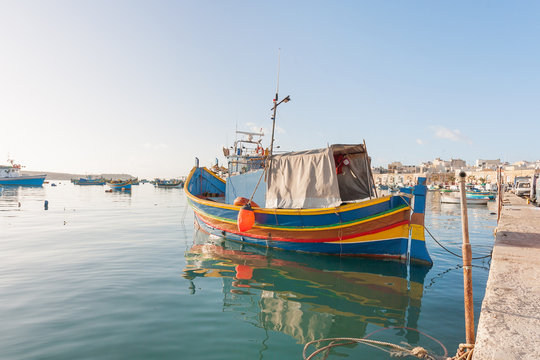 Mediterranean traditional colorful boats luzzu. Fisherman village in the south east of Malta. Early winter morning in Marsaxlokk, Malta.