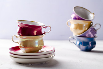 Empty colorful porcelain tableware, cups and plates on lilac, grey background