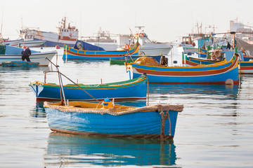 Fototapeta na wymiar Mediterranean traditional colorful boats luzzu. Fisherman village in the south east of Malta. Early winter morning in Marsaxlokk, Malta.