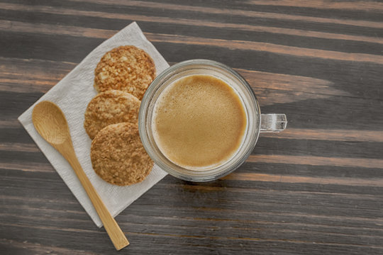 Coffee and cookies on a wooden table with a wooden spoon