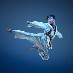 Fotobehang Young boy training karate on blue background © master1305
