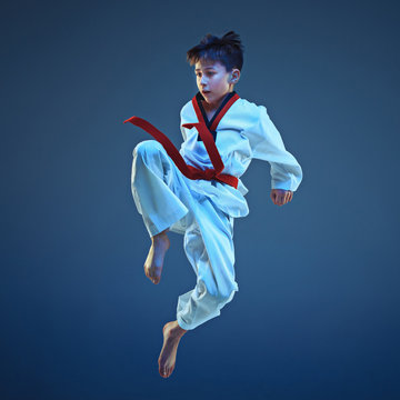 Young boy training karate on blue background