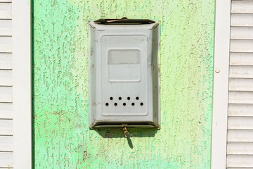 Fototapeta na wymiar Old metal mailbox hangs on green wall