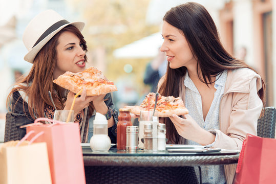 Portrait of two young women eating pizza