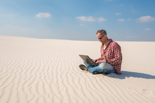 Concerned man with a laptop sits in desert