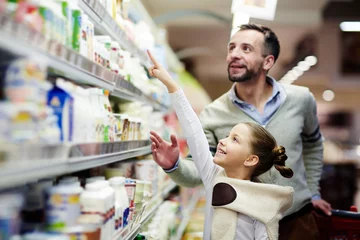 Foto op Plexiglas Happy girl pointing at pack of youghurt on upper shelf in supermarket © pressmaster