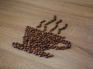 Shape of coffee cup with roasted grains over wooden background