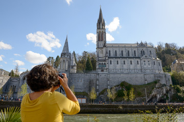 woman photographs the cathedral in Lourdes, France