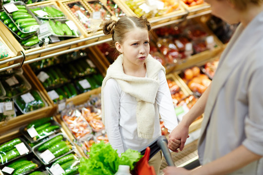 Frowning girl looking at her mother in supermarket