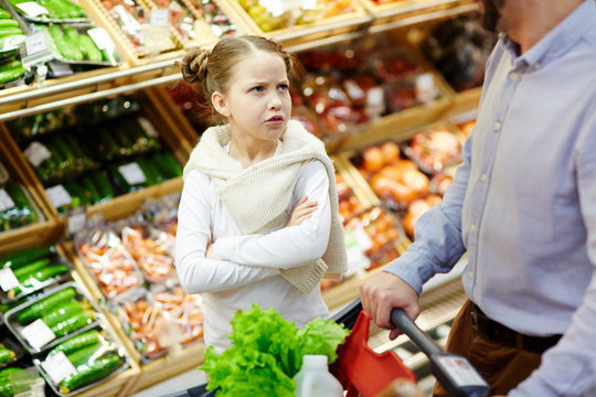Capricious child asking her father to buy something tasty in supermarket