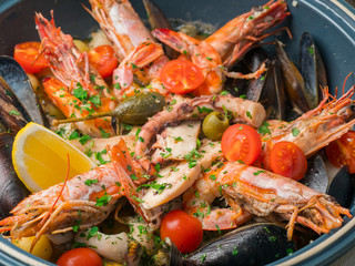 Colorful fresh seafood with vegetables and spices on blue plate in restaurant