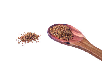Fenugreek seeds on a brass spoon isolated on a white background.
