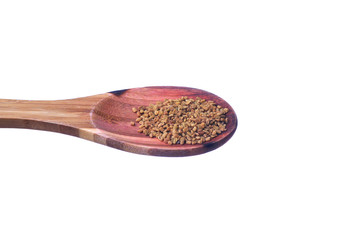 Fenugreek seeds on a brass spoon isolated on a white background.