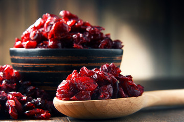 Composition with bowl of dried cranberries on wooden table - obrazy, fototapety, plakaty