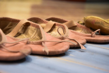 Small used shoes for dance, isolated on wooden background.