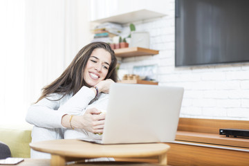 Young beautiful woman sitting on the floor working on laptop. Morning scene