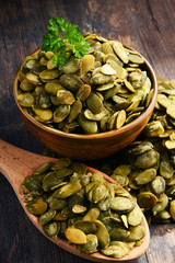 Composition with bowl of pumpkin seeds on wooden table