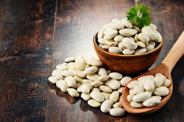 Composition with bowl of white beans on wooden table