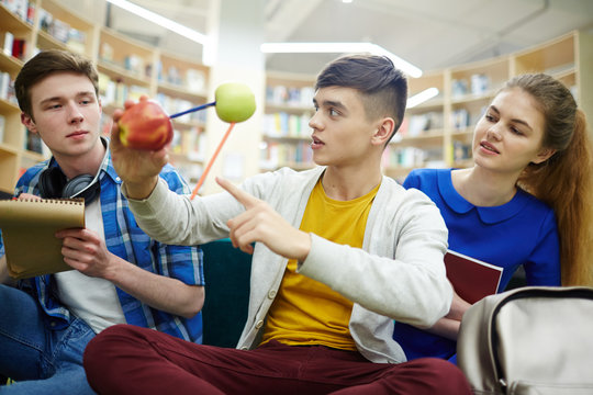 Group of young people studying in library of college: three students working on group project in chemistry making molecule model