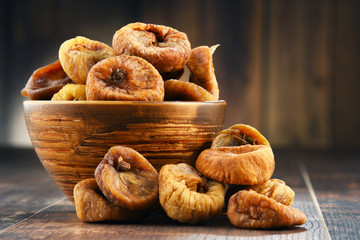 Composition with bowl of dried figs on wooden table