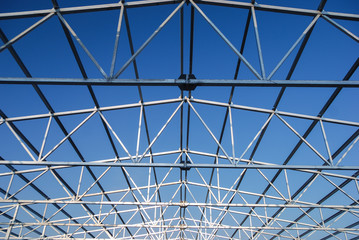 Galvanized steel roof truss construction frames with deep blue sky in the background