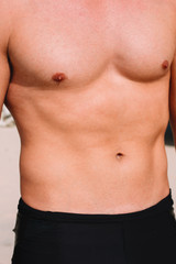 Close up of young muscle fitness man body, during sunshine, on the beach of Bali