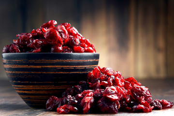 Composition with bowl of dried cranberries on wooden table