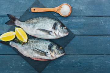  Delicious fresh fish on dark vintage background. Fish with aromatic herbs, spices and vegetables - healthy food, diet or cooking concept