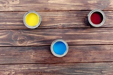 Red yellow and blue paint in jars on a brown wooden stand