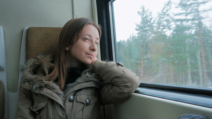 Pensive woman relaxing and looking out of a train window