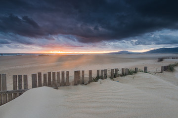 dramatic sunset and storm clouds over beach in Tarifa, Spain