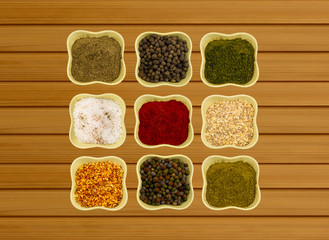 Collection of spices in ceramic bowls on a wooden background fragrant paprika paprika fennel and coriander