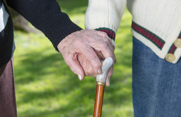 Elderly couple with stick in the garden, hands detail