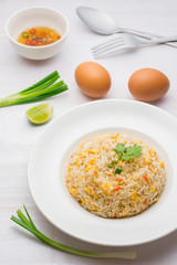 Fried rice with spicy sauce on white wooden background