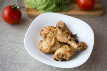 The chicken leg baked in an oven on a glass plate on a gray background