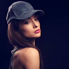 Beautiful sexy young make-up model profile in blue baseball cap with long hair style posing on dark black background. Closeup portrait