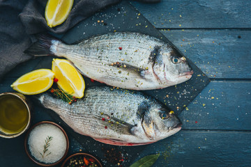 Dorado fish with lemon and spices on a wooden board