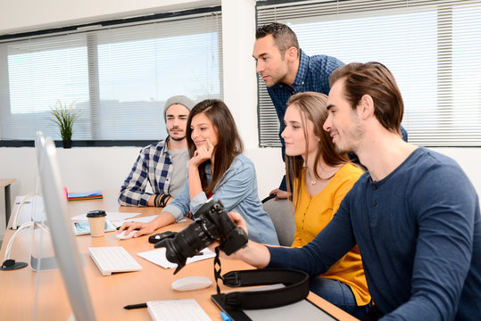 group of five young people student with their teacher in photography school learning photo editing with desktop computer, camera and photo equipment