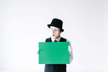 Mime holds green paper in his arms