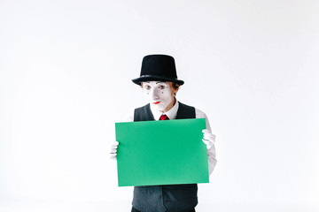 Funny mime holds green paper in his arms