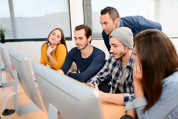 group of five young people student with teacher in computer school classroom learning programming with desktop computer in a row